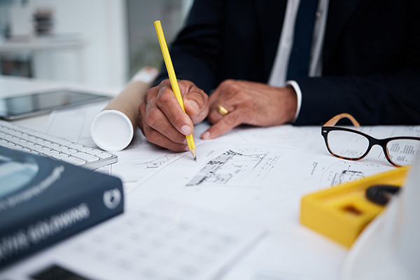 Architect drawing building plans with a pencil